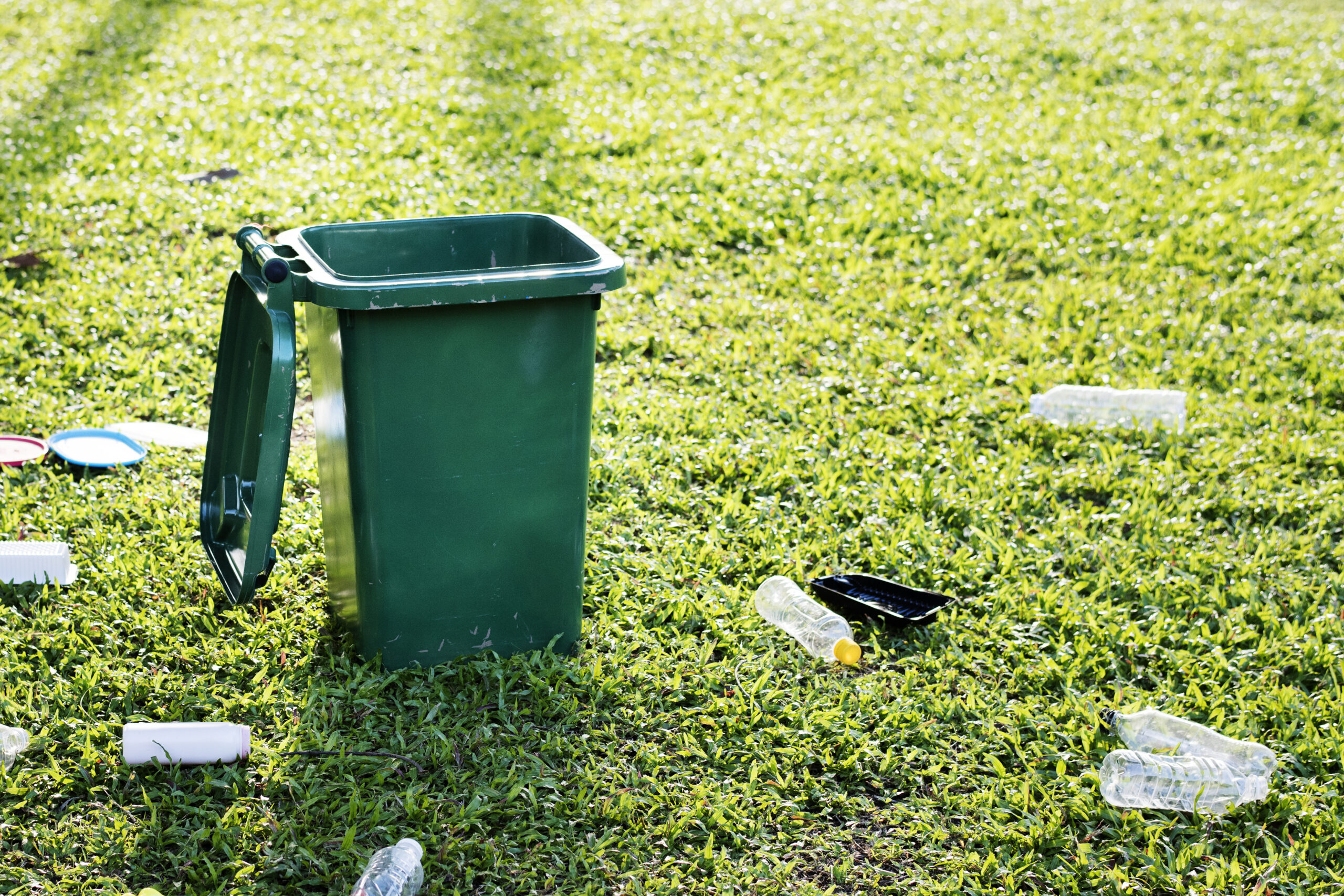 Recycling campaign with green bin and wasted plastic bottles on Recycling campaign with green bin and wasted plastic bottles on the field