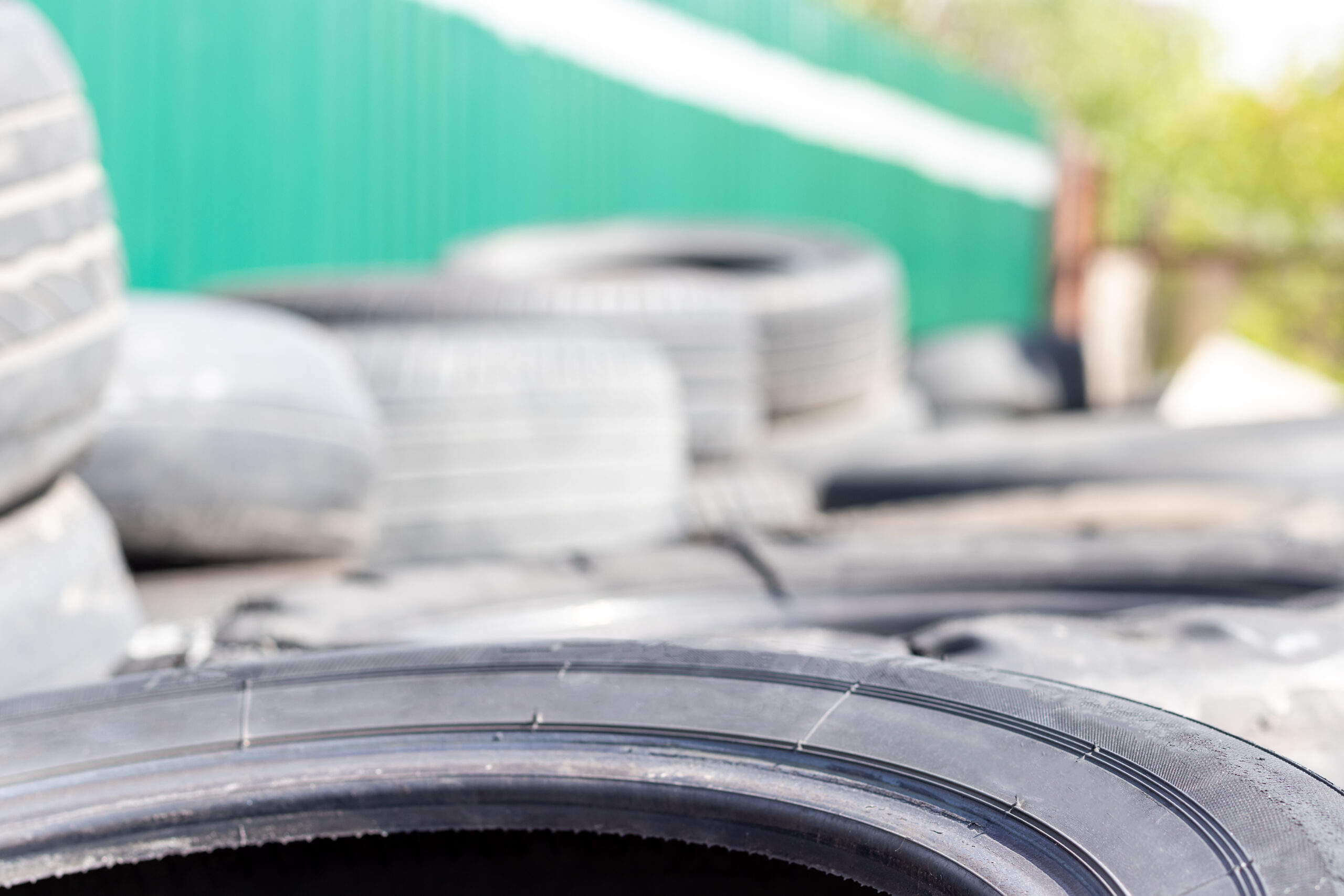Old used car tire near the tire shop against a blurred background with copy space. Selective focus. Closeup view Old used car tire near the tire shop against a blurred background with copy space. Selective focus. Closeup view