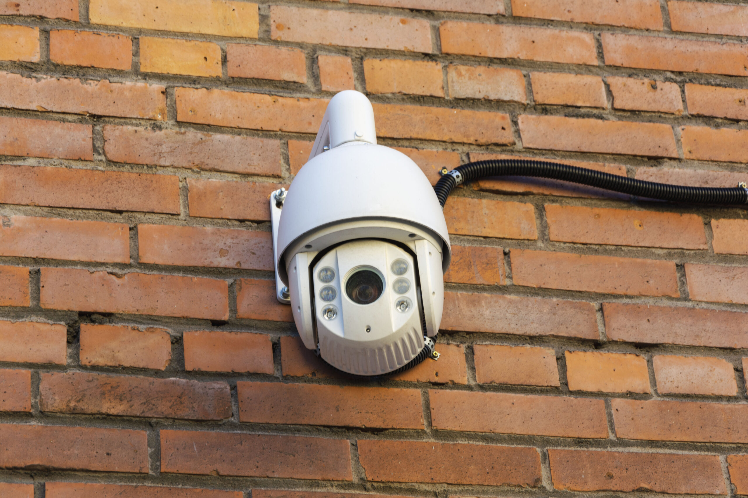 Video surveillance camera on the background of a brick wall. Security concept, video and photo surveillance. Tracking. Search. A place to copy. Protection of private property.