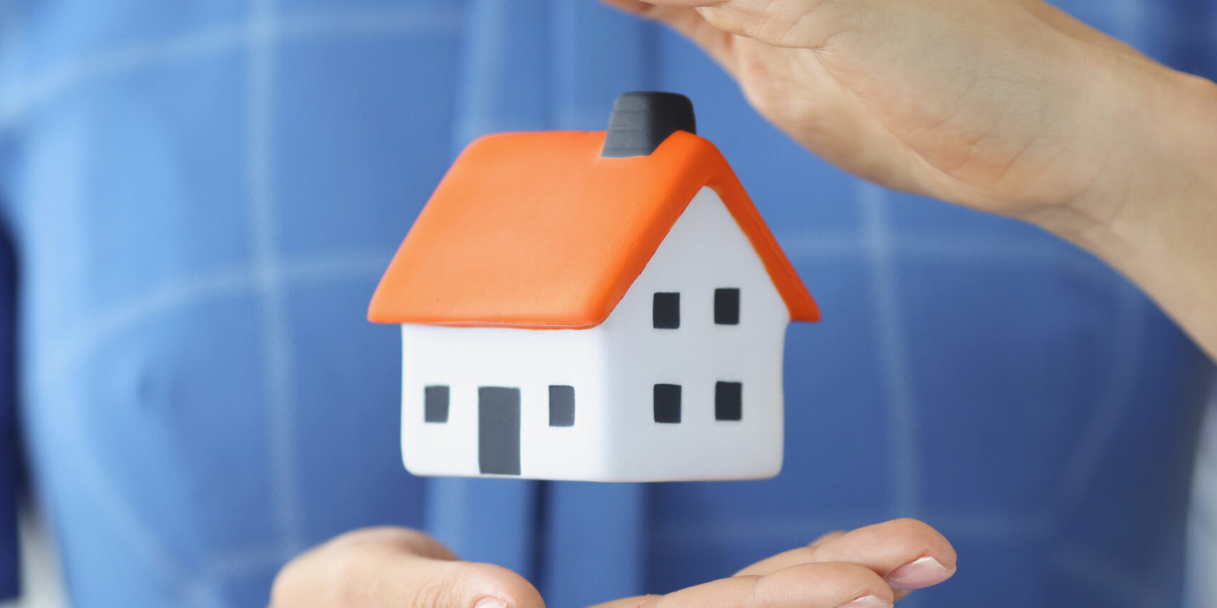 Small house in female hands of air. Home insurance concept
